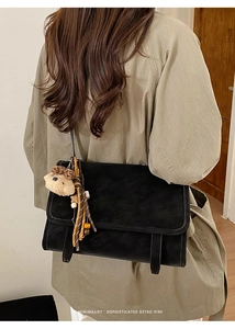 Detail of matte retro tote bag featuring a cute plush bear charm and wooden bead tassels
