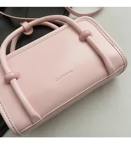 Close-up of pink leather handbag showing delicate texture and debossed brand logo