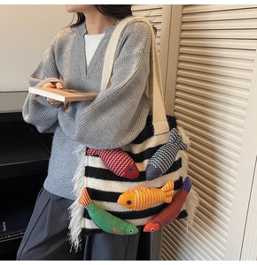 Detail view of striped woven tote bag with colorful 3D fish charms and white tassels