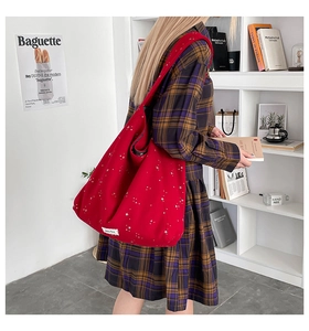 Detail of red canvas tote bag with white stars print and wide shoulder strap