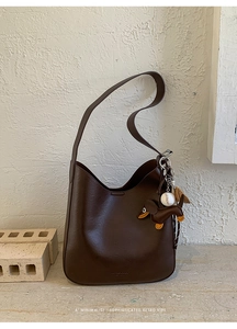 Detail of vintage brown leather hobo bag with dachshund and baseball charms on side