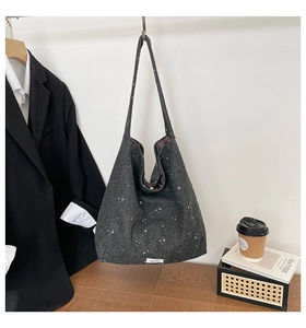 Detail of grey star-patterned tote bag showing textured wool fabric and red inner lining