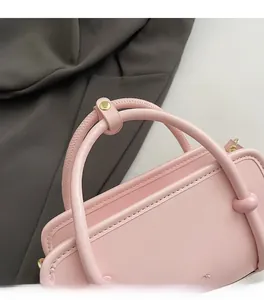 Detail of pink PU leather handbag showing the reinforced handle and gold rivet hardware