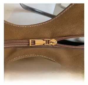 Close-up of golden zipper and contrast stitching on brown matte leather tote bag