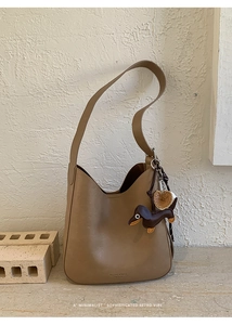 Detail of tan leather Hobo bag featuring a cute dachshund charm and embossed brand logo