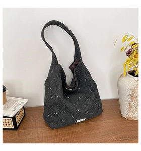 Detailed close-up of dark grey star pattern tote bag on wooden surface with decor