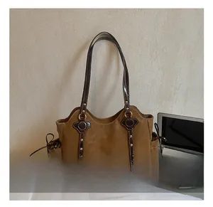Detail view of brown faux suede tote bag featuring gold studs and side bow drawstring knots