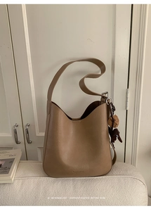 Detail of tan leather bucket bag with cute bear charm and embossed logo on bottom