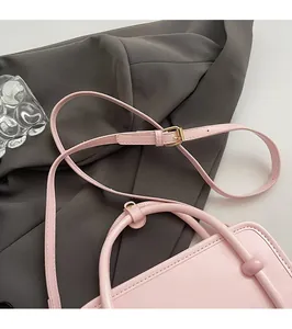 Detail of adjustable thin shoulder strap and gold hardware on cream leather crossbody bag