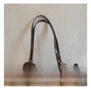 Close-up of brown tote bag showing contrast stitching and gold rivet reinforcement