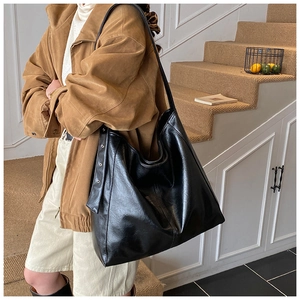 Detail view of large black glossy PU leather tote bag with stylish rivet side accents
