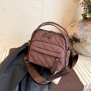 Macro detail of dark brown quilted nylon texture and multi-zipper pocket on the shoulder bag