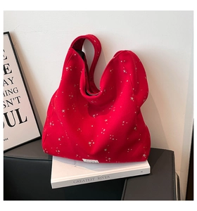Detail of red fabric tote bag with silver star patterns and minimalist brand label