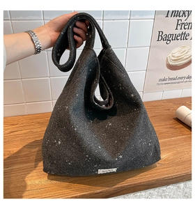 Detail of dark grey tote bag with star patterns and thick texture shown in a lifestyle scene
