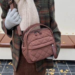 Brown quilted crossbody bag with diamond patterns worn with a winter coat and scarf