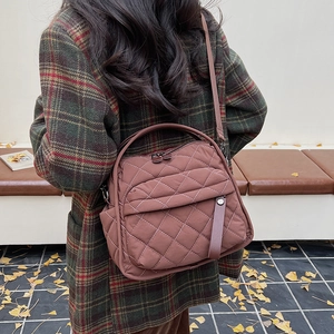 Macro detail of brown quilted crossbody bag featuring diamond stitching and dual zippers