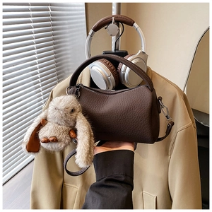 Detail of coffee brown crossbody bag with lychee texture and plush bunny charm