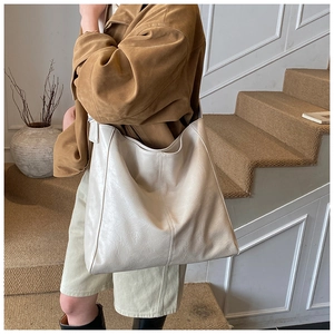 Detailed view of a large cream tote bag with soft leather texture on a beige staircase