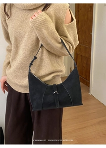 Detail of minimalist black matte suede dumpling bag with silver buckle and shoulder strap