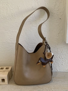 Vintage khaki leather hobo bucket bag with wide strap and dog charm accessory