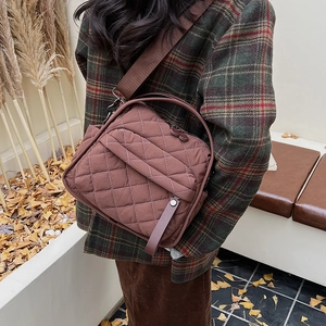 Detailed side view of brown quilted crossbody bag with adjustable wide strap on model