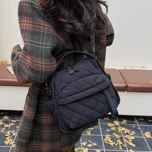 Detail of black quilted nylon crossbody bag featuring diamond stitching and zip closure