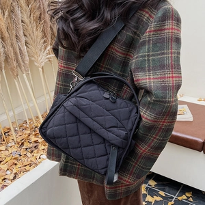 Side view of a black quilted crossbody bag showing texture and adjustable strap on a model