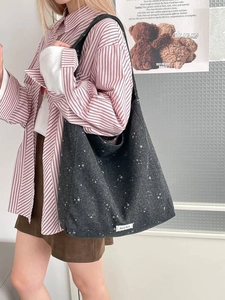 Large dark grey star print tote bag shown on model with a stylish casual look