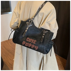 Detail of black suede tote bag featuring Cute Puppy embroidery and metal rivet accents
