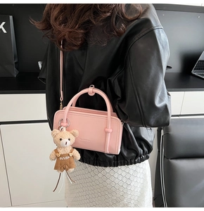 Detailed view of pink crossbody bag with a cute bear keychain worn over a black leather jacket