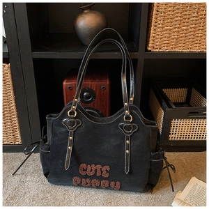 Detail of a large black tote bag with brown furry Cute Puppy letters and white stitching