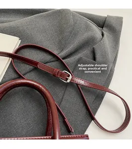 Detail of adjustable leather strap with silver buckle on dark wine red handbag