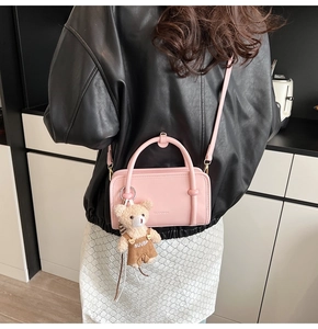 Detailansicht der rosa rechteckigen Umhängetasche mit Bärenanhänger an einem Modell
