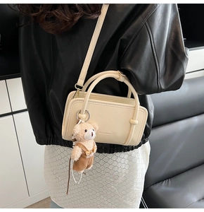 Detail of cream mini shoulder bag with bear pendant and adjustable leather strap