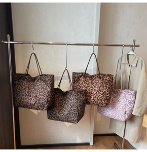 Detailed display of four leopard print tote bags in various colors on a metal hanger