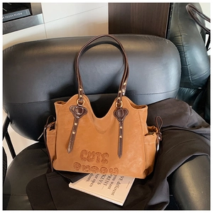 Macro detail of the CUTE plush lettering and textured leather on the brown tote bag