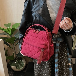Detail of red quilted rhombus shoulder bag with wide strap and zip closure on model