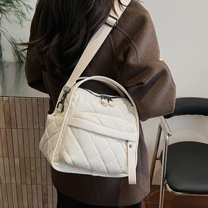 Rear view of a model wearing a white quilted crossbody bag with adjustable wide straps