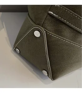 Macro detail of olive green textured leather tote bag bottom with silver metal feet