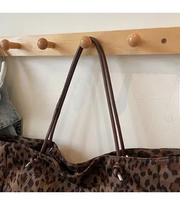 Close-up of leopard print tote bag with brown leather straps and knotted metal buckles