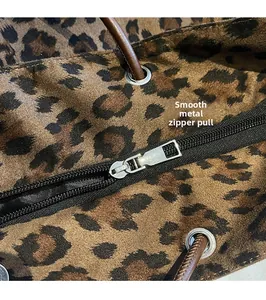 Close-up of smooth metal zipper and brown leather strap on leopard print suede tote bag