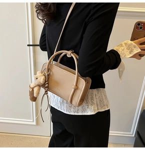 Chic beige crossbody bag with plush bear charm worn by model for size reference