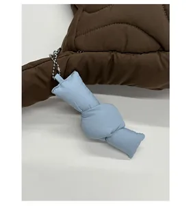 Dettaglio borsa trapuntata marrone con ciondolo a contrasto blu chiaro a forma di cuscino