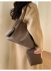 Détail du sac fourre-tout marron foncé avec texture cuir et pochette assortie sur mannequin