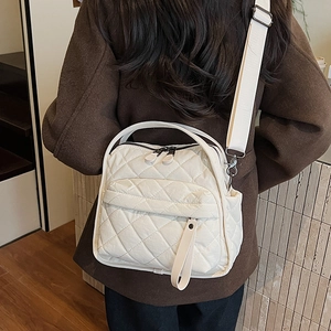 Detail of white quilted nylon shoulder bag with wide strap over a brown wool coat