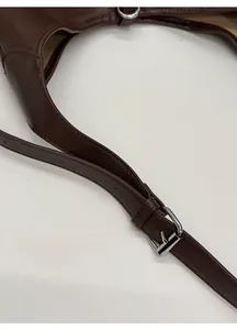 Detail view of adjustable dark brown leather shoulder strap with silver buckle closure