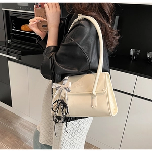 Detail of off-white leather shoulder bag with lace bow and pearl charm decoration