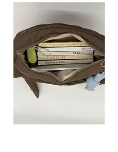 Dettaglio interno borsa trapuntata marrone con libri, tablet e ciondolo a forma di orso