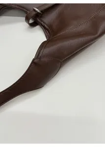 Detail of reinforced handle base and precision stitching on dark brown leather tote bag