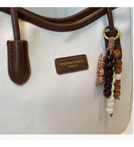 Detail of white PU leather tote with brown trim and vintage colorful beaded tassel charm